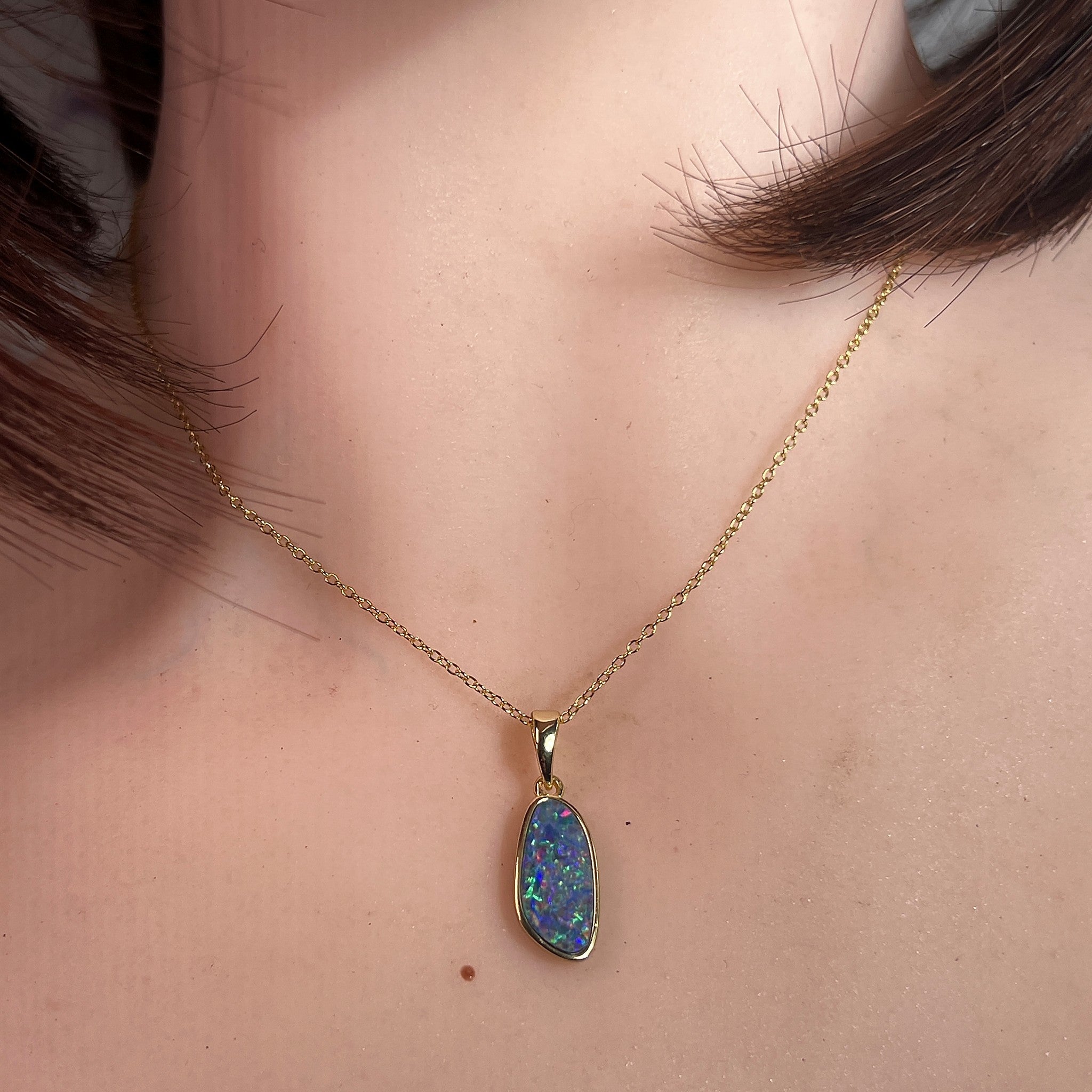 freeform Australian opal doublet pendant in yellow gold-plated silver, worn at the neck