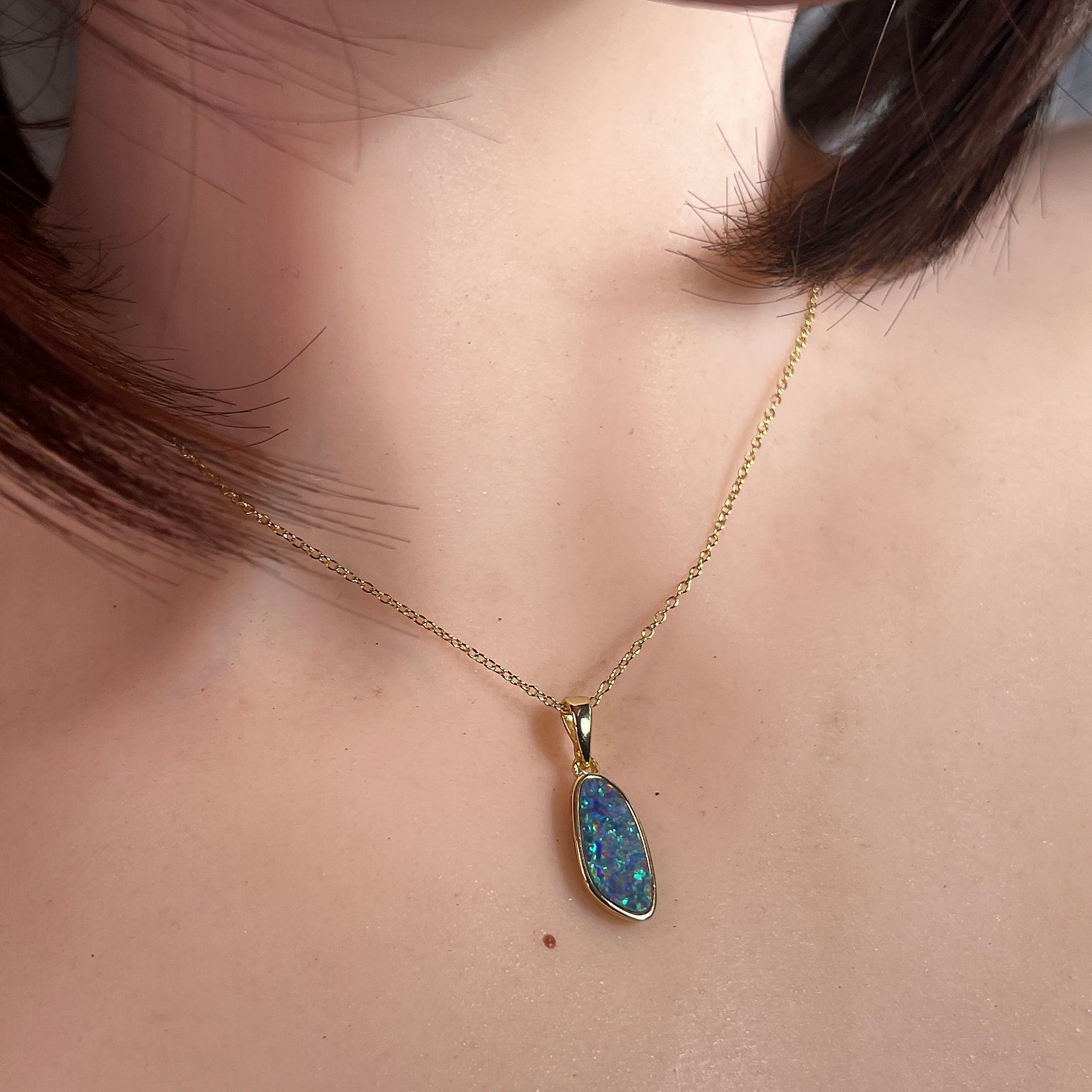 15 x 7mm freeform Australian opal doublet pendant worn at the neck, yellow gold-plated silver