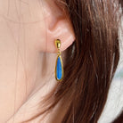 pear-shaped Australian opal doublet earrings in yellow gold-plated silver, worn on the ear