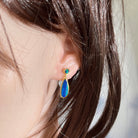 16.5 x 7mm and 5mm round Australian opal doublet earrings worn on the ear, yellow gold-plated silver