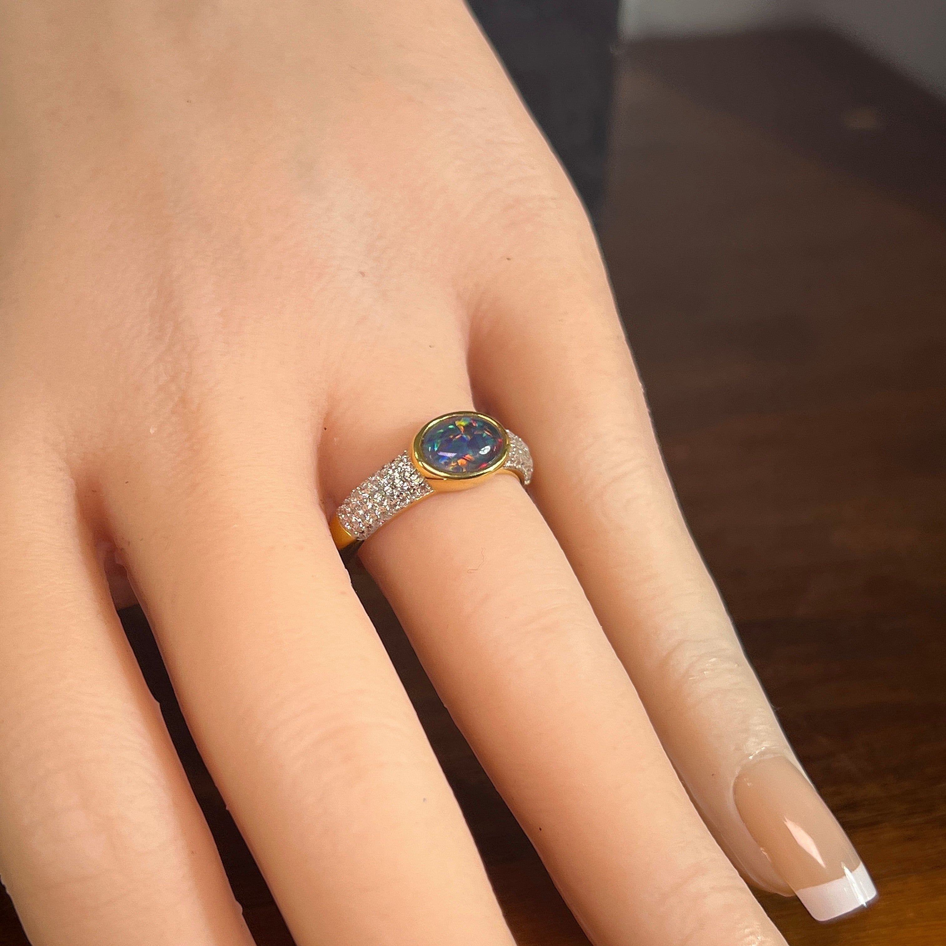 8 x 6mm oval Australian opal triplet ring on the hand, yellow gold-plated silver